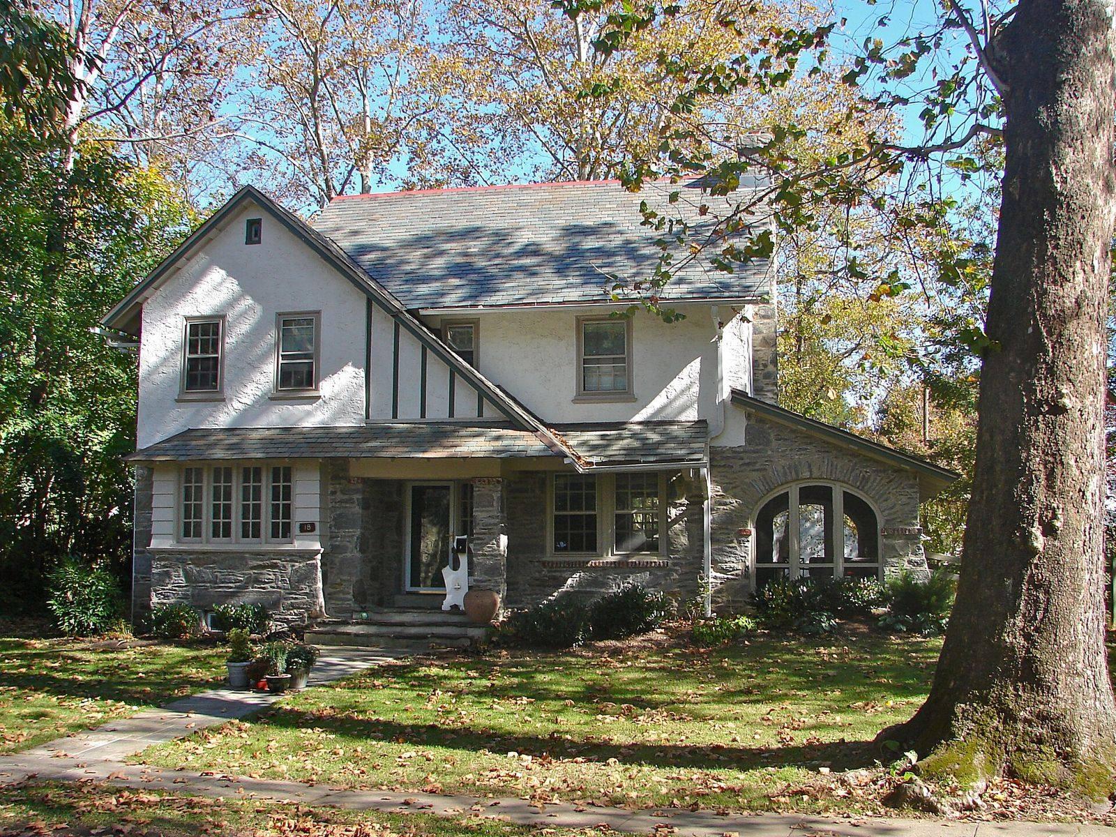 A stucco and stone house with a front porch under a large sycamore in the Narbrook Park Historic District, Narberth