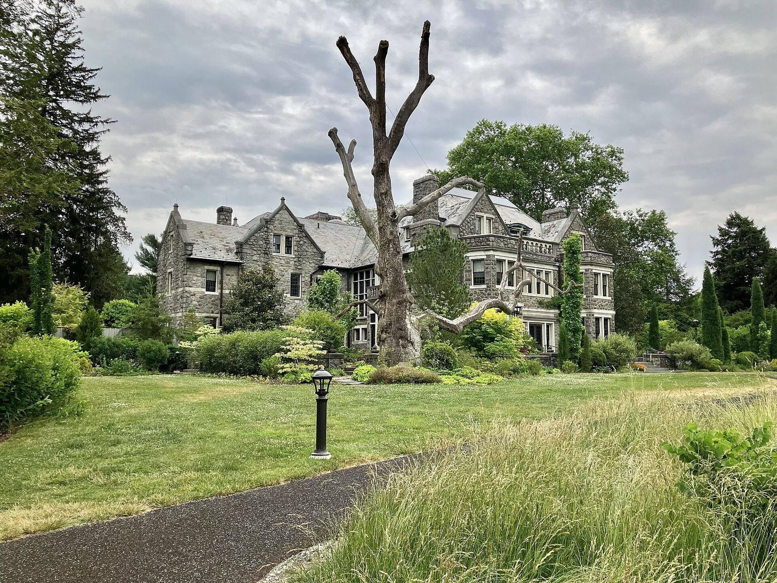 The Tudor Revival stone mansion at Stoneleigh, a public garden in Villanova, seen across a meadow